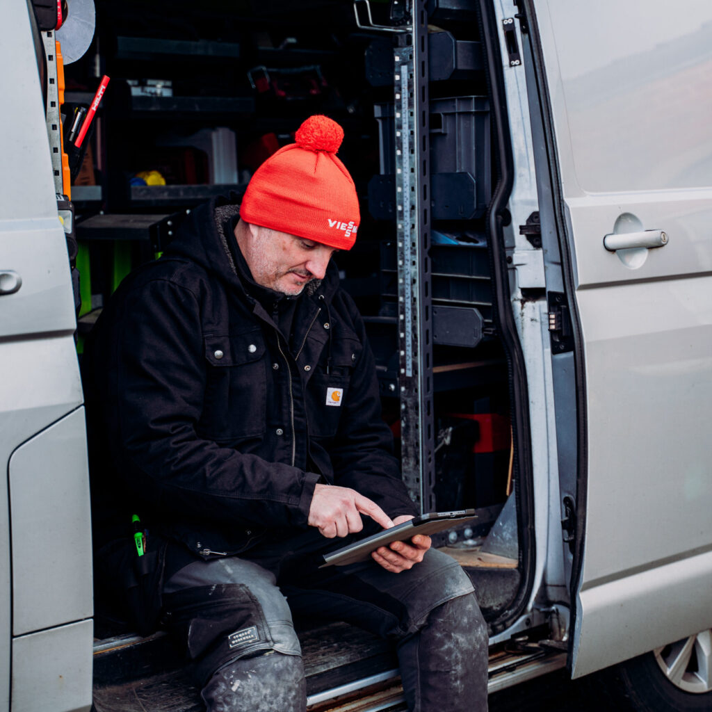 man in van using job management software on tablet