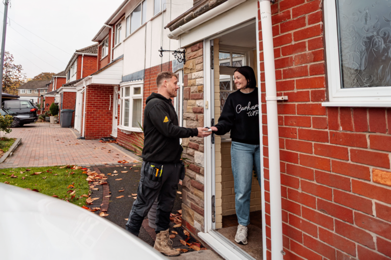 A tradesperson shaking hands with a happy customer at her front door
